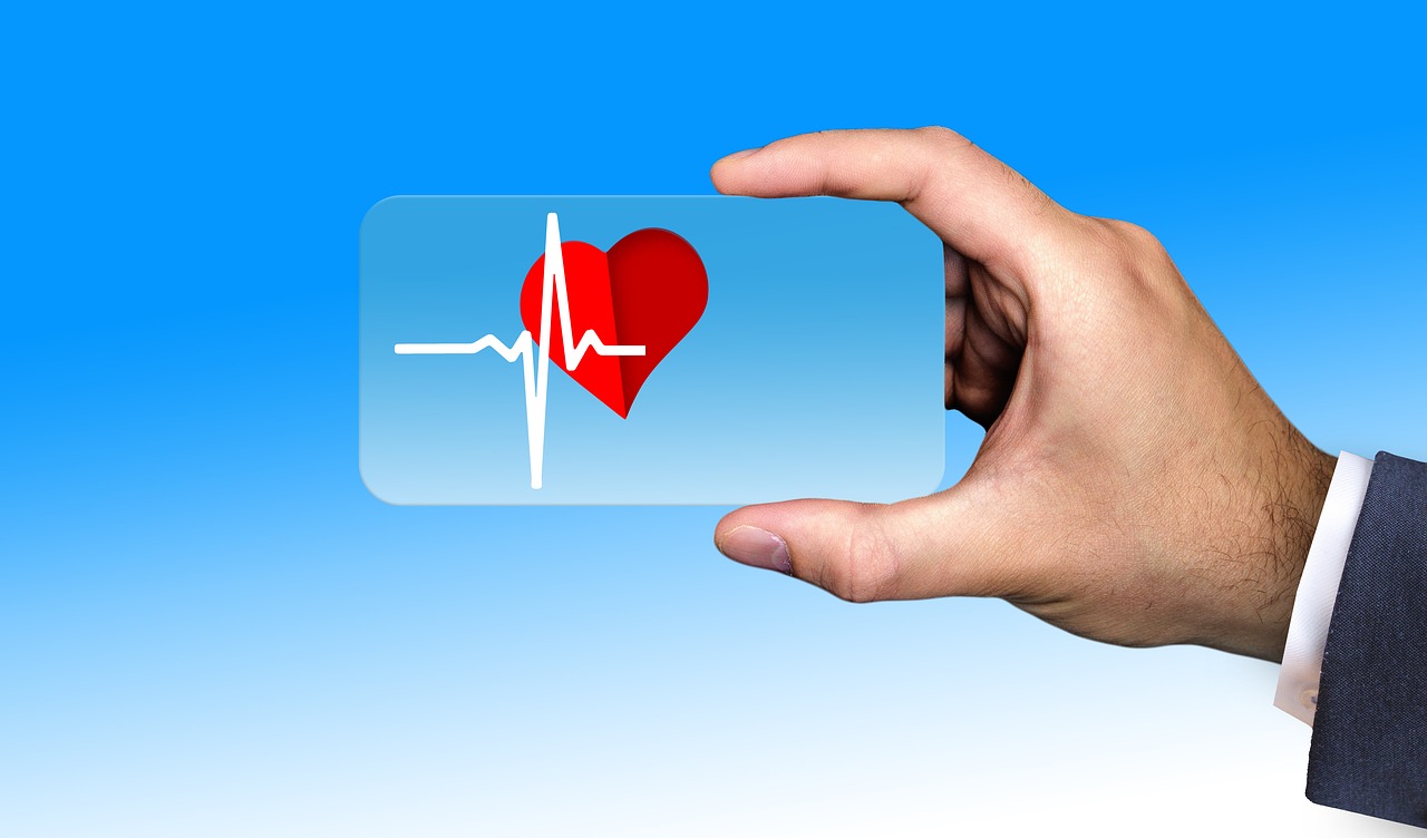 A man's hand holding a credit card size card with a picture of a heart on it and a line showing heart rhythm.